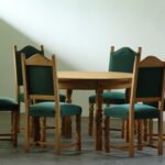 Round vintage Danish brutalist oak dining table with green velvet high-back chairs, carved baluster legs, Henning Kjærnulf style, 1960s
